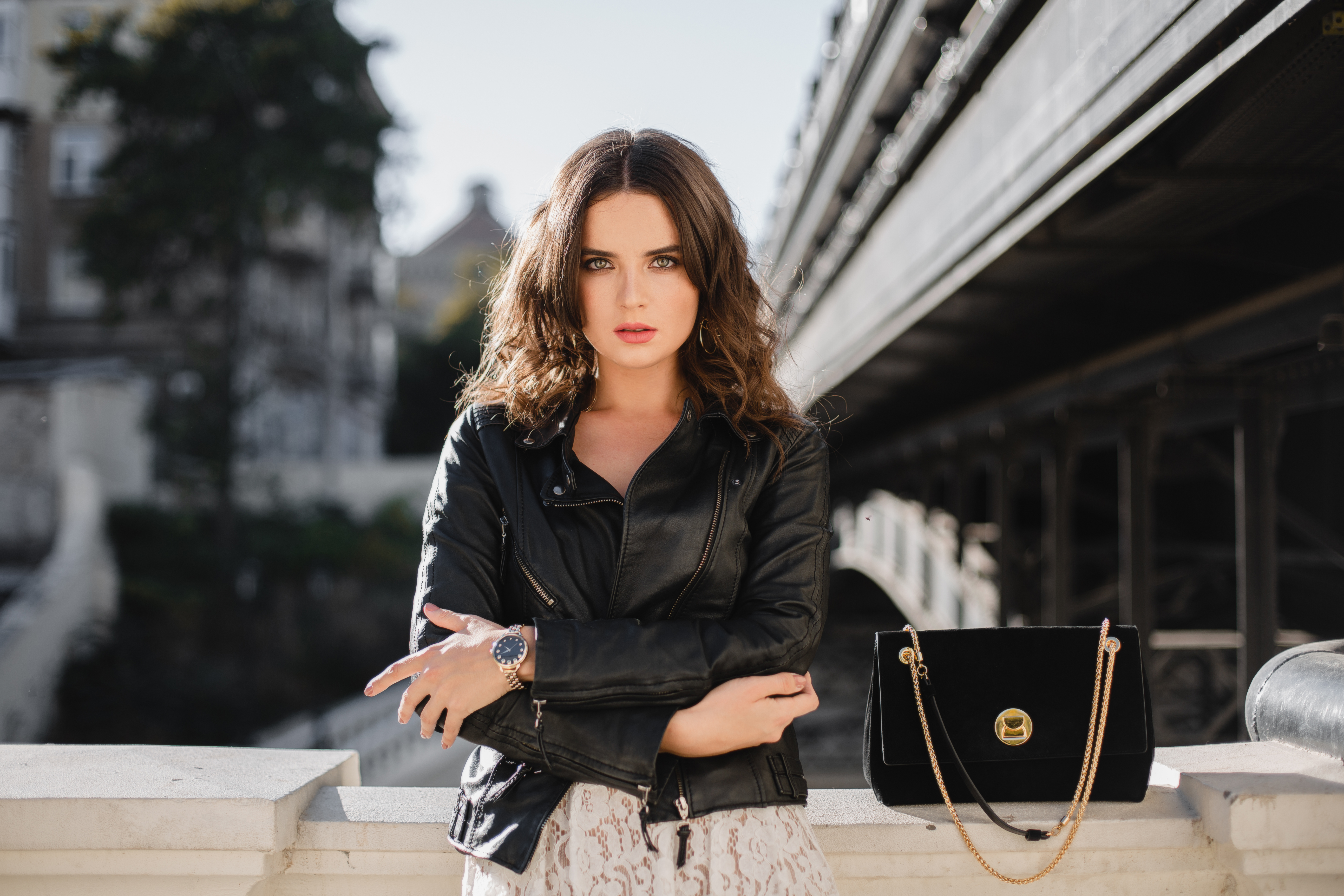attractive stylish woman posing in street in fashionable outfit, suede handbag, wearing black leather jacket and white lace dress, spring autumn style, romantic mood, warm weather, sunny